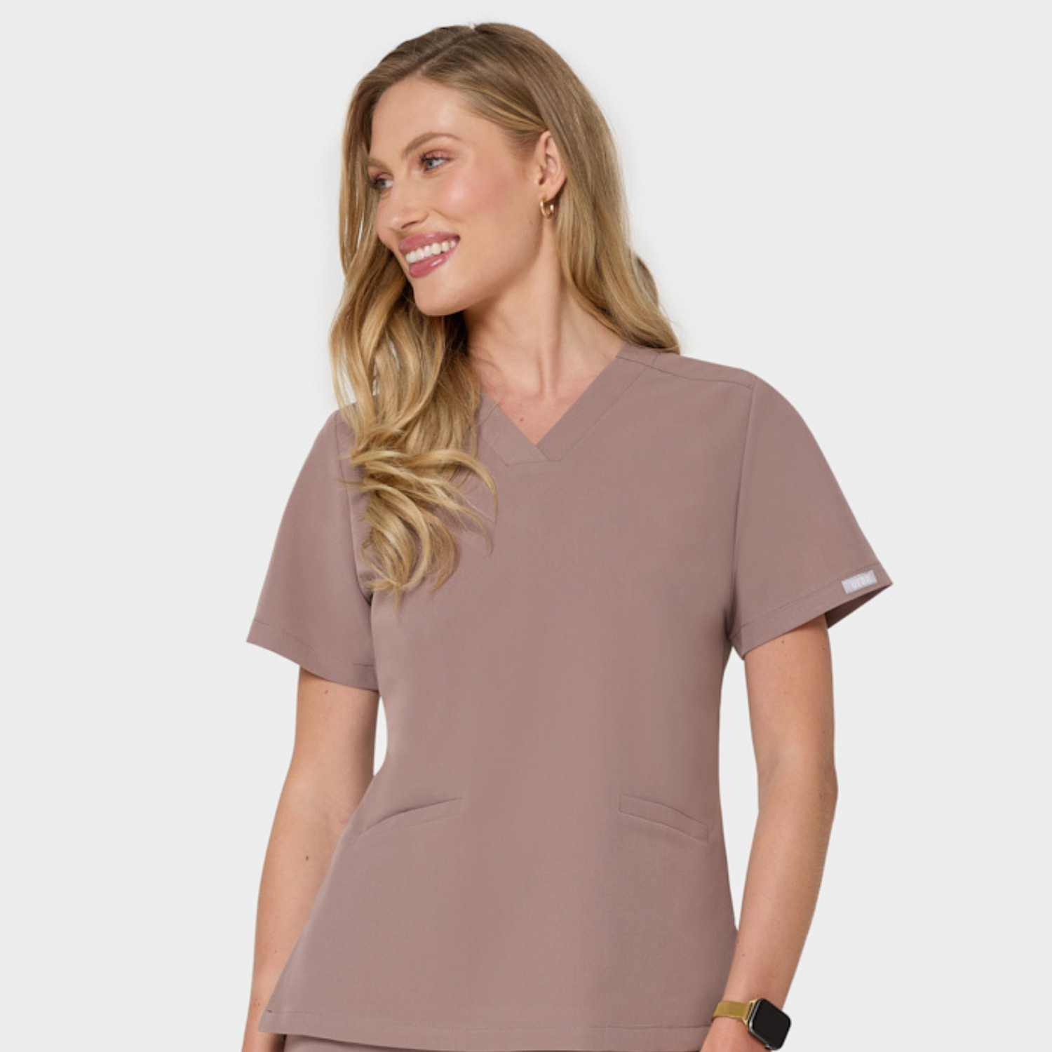 Bluza medyczna Emily w kolorze LIGHT BROWN od Vena Uniformy.
Modelka stoi na jasnym tle w bluzie z krótkim rękawem.