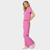 Bluza medyczna Gaja crop w kolorze Disco Pink od Vena Uniformy.
Modelka stoi na jasnym tle w komplecie medycznym: bluza z krótkim rękawem oraz szerokie spodnie, zestawione z beżowymi sneakersami.