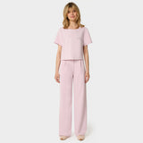 Bluza medyczna Gaja crop w kolorze PASTEL PINK od Vena Uniformy.
Modelka stoi na jasnym tle w pastelowym komplecie medycznym: bluza z krótkim rękawem oraz szerokie spodnie, zestawione z beżowymi sneakersami.