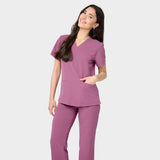 Modelka w bluzie medycznej Emily w kolorze Berry Crush, z dekoltem w serek, krótkim rękawem i kieszeniami – elegancka i funkcjonalna odzież medyczna dla kobiet.