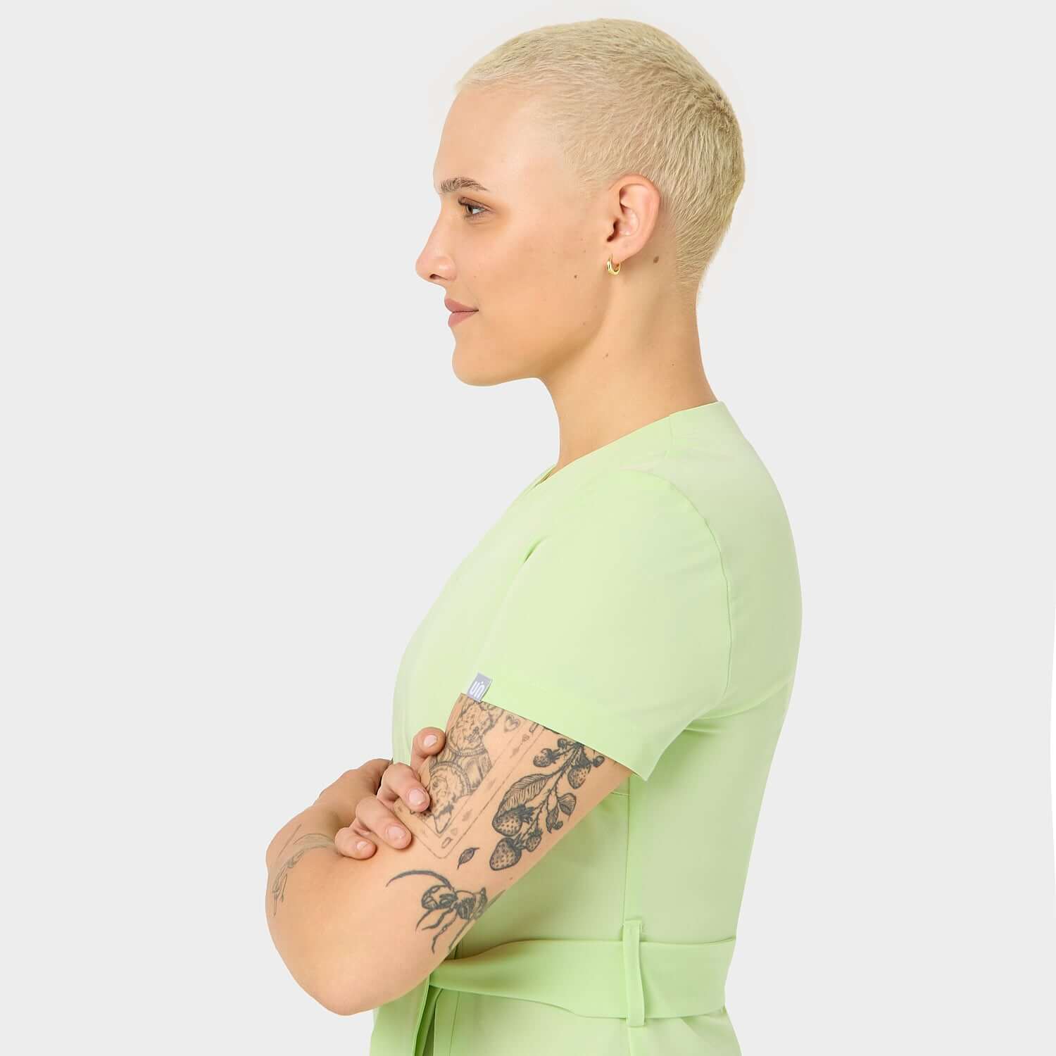 Wiązany fartuszek Sophia w kolorze Matcha z boku: Widok z boku wiązanego fartuszka medycznego Sophia w modnym kolorze Matcha, ukazujący elegancki krój i dopasowanie, idealny dla profesjonalistek w branży medycznej i kosmetycznej.