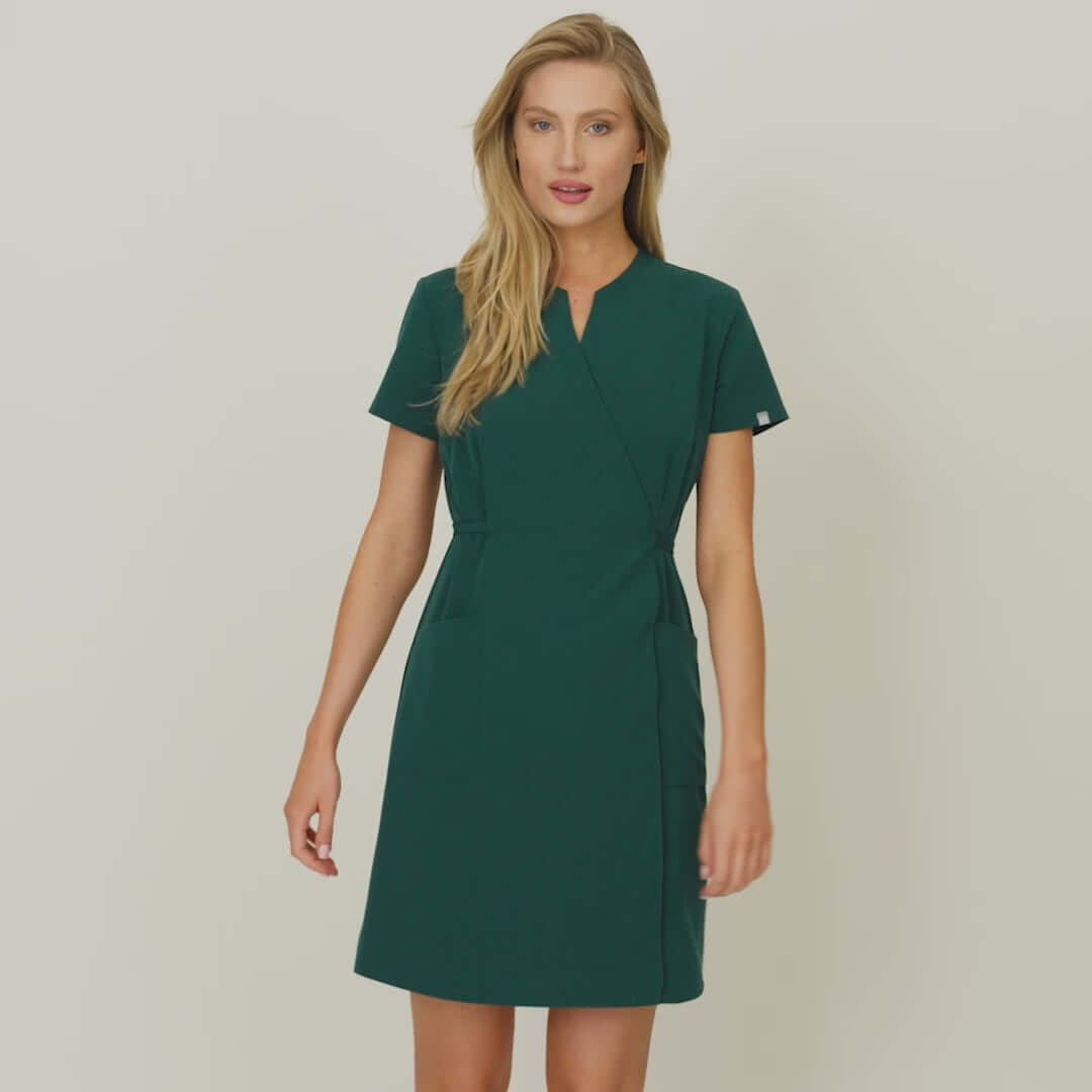 Video prezentujące wiązaną sukienkę medyczną damską KATE w kolorze butelkowej zieleni Moss Green. Modelka pokazuje sukienkę z przodu, z tyłu oraz w ruchu, zwracając uwagę na detale produktu. Sukienka idealnie dopasowuje się do różnych sylwetek, zapewniając komfort i elegancję w pracy medycznej.