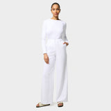 Damskie spodnie medyczne Aura WHITE o szerokich nogawkach, z wysoką talią, na modelce w białej bluzce longsleeve.